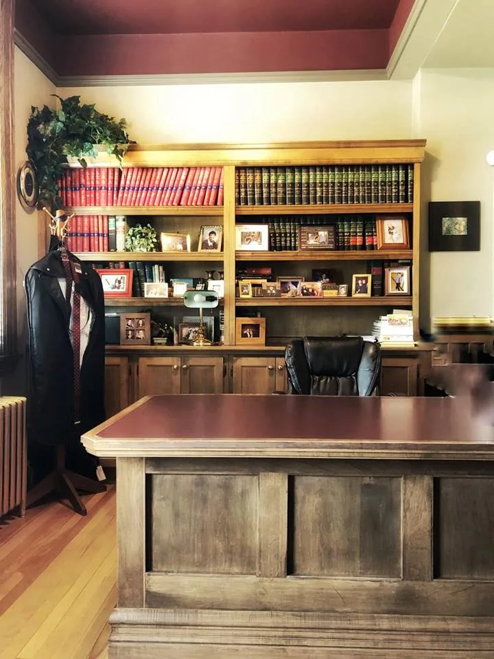 Jim Dixon's office in the Old Court House: an oak desk, a coat and tie on the stand, and shelves of family photographs.